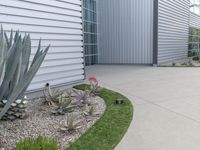 a concrete walkway that leads to a garage and a flowerbed at the side of the house