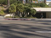 a car driving down the road in front of a large building surrounded by palm trees