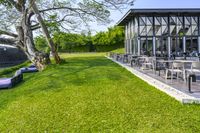 patio with lounge chairs, tables, and a water tank in the background surrounded by green grass