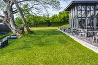 patio with lounge chairs, tables, and a water tank in the background surrounded by green grass