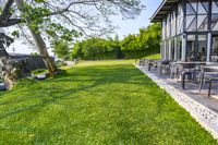 patio with lounge chairs, tables, and a water tank in the background surrounded by green grass