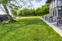 patio with lounge chairs, tables, and a water tank in the background surrounded by green grass