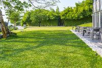 patio with lounge chairs, tables, and a water tank in the background surrounded by green grass