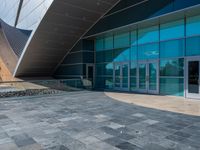 a large glass building with a very pretty curved roof, which looks as if it is built from granite blocks