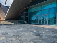 a large glass building with a very pretty curved roof, which looks as if it is built from granite blocks