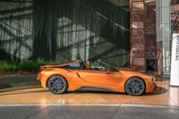 a bright orange convertible sports car is parked next to the water fountain at this hotel