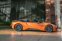 a bright orange convertible sports car is parked next to the water fountain at this hotel