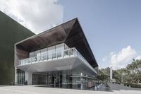 an artistic building with glass and wood exterior, and balcony over the sidewalk next to it