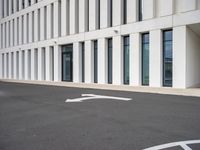 empty parking lot with white lines in the middle of it and a building behind it