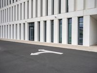 empty parking lot with white lines in the middle of it and a building behind it