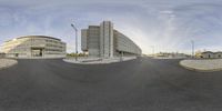 the 360 - pan of an empty street in front of building complex with a cloudy blue sky