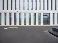 the outside of a white building with lots of windows and a bench on the ground