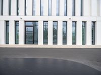 the outside of a white building with lots of windows and a bench on the ground