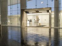 an empty lobby with several glass doors and a window in the middle with rain coming on it