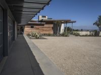 modern architecture in the desert with mountains and a blue sky in the background and the sidewalk to the right