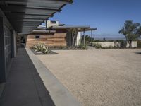 modern architecture in the desert with mountains and a blue sky in the background and the sidewalk to the right