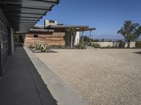 modern architecture in the desert with mountains and a blue sky in the background and the sidewalk to the right