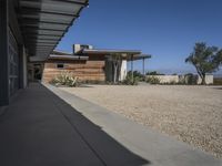 modern architecture in the desert with mountains and a blue sky in the background and the sidewalk to the right