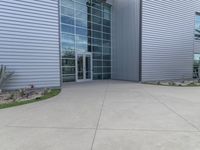 two men are walking past a building with large windows and grass around the door,