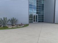 two men are walking past a building with large windows and grass around the door,