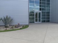 two men are walking past a building with large windows and grass around the door,