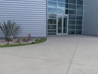 two men are walking past a building with large windows and grass around the door,