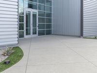 two men are walking past a building with large windows and grass around the door,