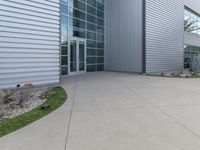 two men are walking past a building with large windows and grass around the door,