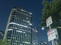 a couple of tall buildings that are lit up at night as seen from the ground