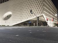 the large building has many triangular shapes in front of it at night time in front of a stop light