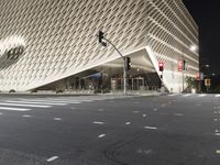 the large building has many triangular shapes in front of it at night time in front of a stop light