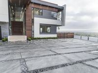 a large gray patio that is outside of a house with concrete floors and walls, and stone paving