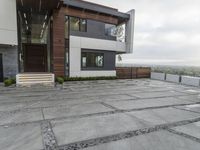 a large gray patio that is outside of a house with concrete floors and walls, and stone paving