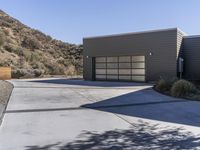 two garages in a house with a fence around them and mountains behind them and a wooden fence outside