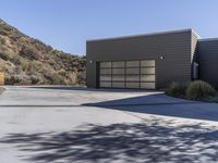 two garages in a house with a fence around them and mountains behind them and a wooden fence outside