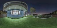 a circular building in the night time with grass and lights shining on it and a few steps down to it