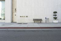 a bench is sitting near the curb in front of the building with no people on it