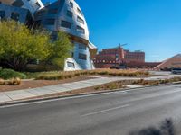 a very cool looking building sitting next to a road and some trees in the foreground