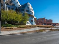 a very cool looking building sitting next to a road and some trees in the foreground