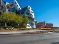 a very cool looking building sitting next to a road and some trees in the foreground