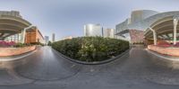 a curved building that has red and white flowers around it in front of it is a green bushy shrub