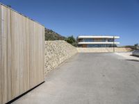 the driveway leading to a modern house on the top of a mountain in spain with a fence around the entrance