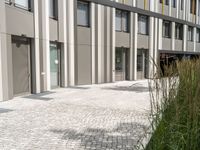 a city building with windows and doors, a brick path and grass in front of it