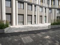 a bench on the outside patio of a large modern building near trees and other plants