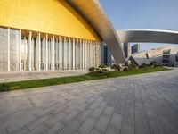 the building has multiple curved sections on each side of it, with grass between them