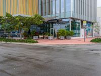 a empty street that is next to a large office building that has colorful buildings on the sides