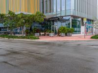 a empty street that is next to a large office building that has colorful buildings on the sides