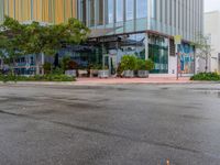 a empty street that is next to a large office building that has colorful buildings on the sides