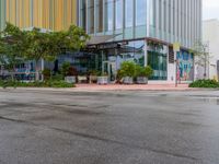 a empty street that is next to a large office building that has colorful buildings on the sides