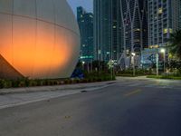 a woman walks past an orange sphere building, with palm trees nearby, in a city